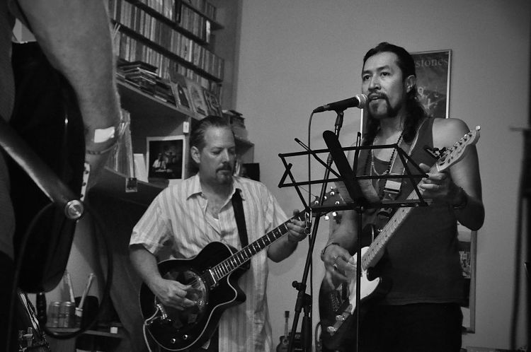 Un ensayo de Carlos Elliot Jr a blanco y negro cantando desde la sala con sus amigos
