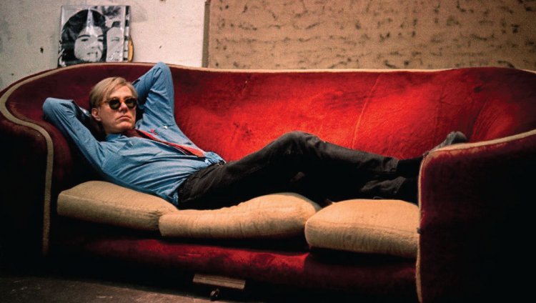 Tacones, pelucas y Warhol Foto: Bob Adelman. Andy Warhol sentado en un sofá de terciopelo rojo en "The Factory".
